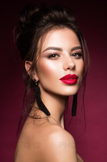 Gorgeous Young Brunette Woman face portrait. Beauty Model Girl with bright eyebrows, perfect make-up, red lips, touching her face. Sexy lady makeup for party