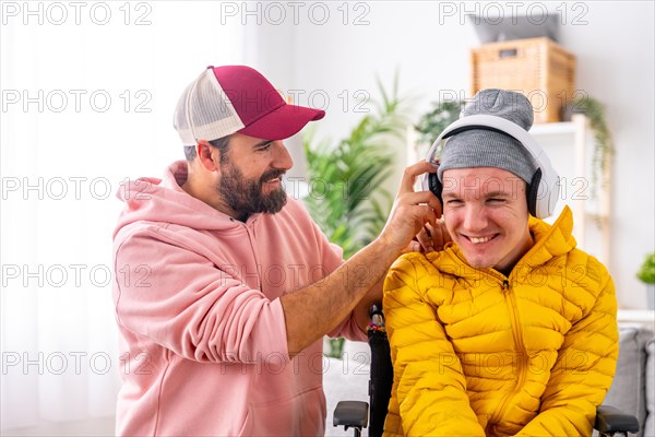 Happy disabled man listening to music using headphones with caregiver at home