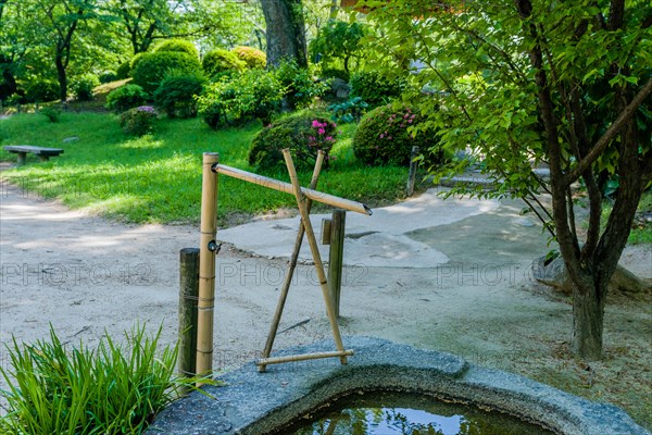 Stone water basin with bamboo pluming in Japanese garden in Hiroshima, Japan, Asia