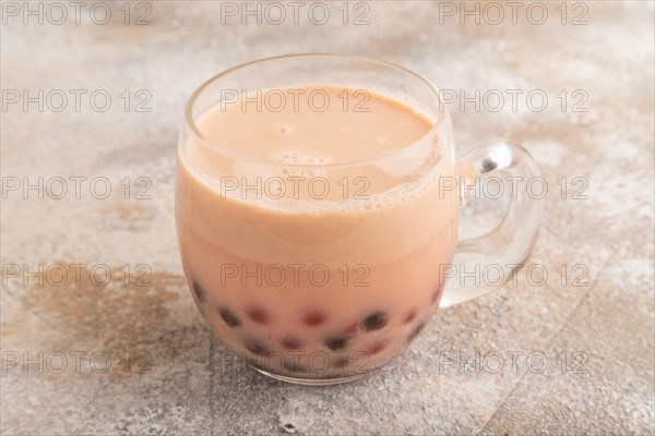 Bubble tea with pistachio and caramel in glass on brown concrete background. Healthy drink concept. Side view, close up