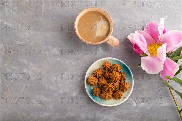 Homemade soft caramel fudge candies on blue plate and cup of coffee on gray concrete background, peony flower decoration. top view, flat lay, copy space