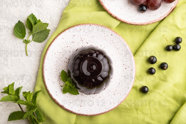 Black currant and grapes jelly on gray concrete background and green linen textile. top view, flat lay, close up