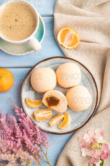 Japanese rice sweet buns mochi filled with tangerine jam and cup of coffee on a blue wooden background and linen textile. top view, flat lay, close up
