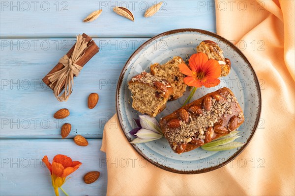 Caramel and almond cake with cup of coffee on blue wooden background and orange linen textile. top view, flat lay, close up