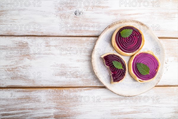 Sweet tartlets with jelly and milk cream on a white wooden background. top view, flat lay, copy space