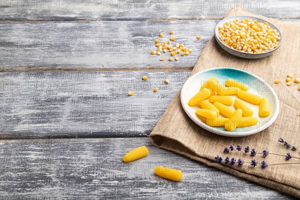 Jelly corn candies on gray wooden background and linen textile. copy space, side view