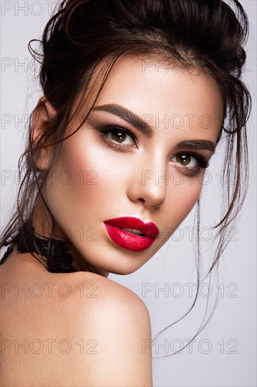 Gorgeous Young Brunette Woman face portrait. Beauty Model Girl with bright eyebrows, perfect make-up, red lips, touching her face. Sexy lady makeup for party