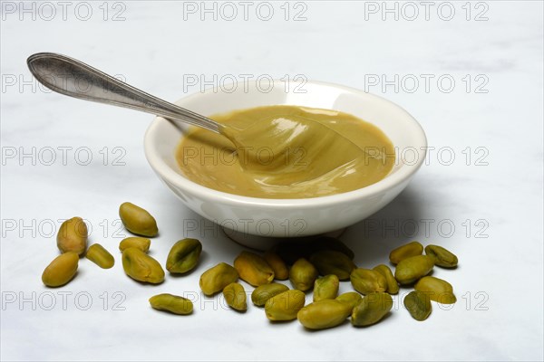 Pistachio cream in small bowls with spoon, pistachios