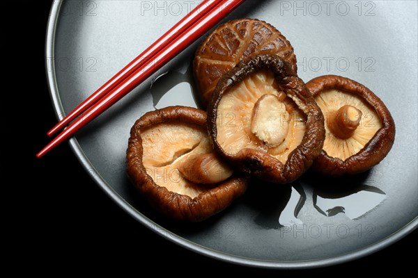 Dried and soaked shiitake mushrooms on a plate with chopsticks