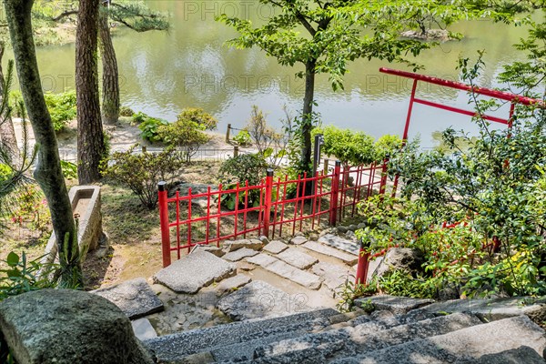 Torii Shinto gate under shade trees in Japanese garden in Hiroshima, Japan, Asia