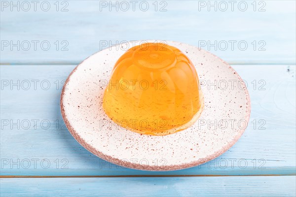 Apricot orange jelly on blue wooden background. side view, close up