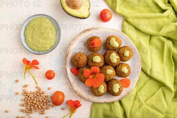 Falafel with guacamole on white concrete background and green linen textile. Top view, flat lay, close up
