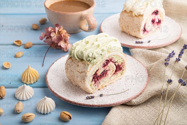 Roll biscuit cake with cream cheese and jam, cup of coffee on blue wooden background and linen textile. side view, close up