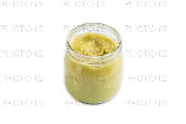 Baby puree with vegetable mix, broccoli, tomatoes, cucumber, avocado infant formula in glass jar isolated on white background. Side view, close up, artificial feeding concept