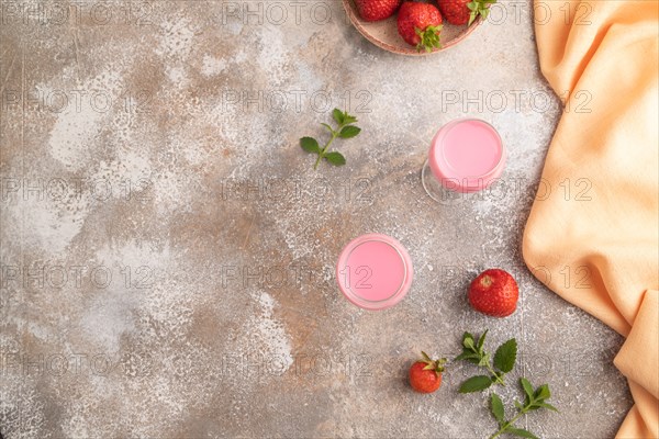 Sweet strawberry liqueur in glass on a gray concrete background and orange textile. top view, copy space, flat lay