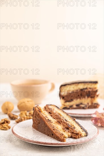 Chocolate biscuit cake with caramel cream and walnuts, cup of coffee on gray concrete background. side view, close up, selective focus