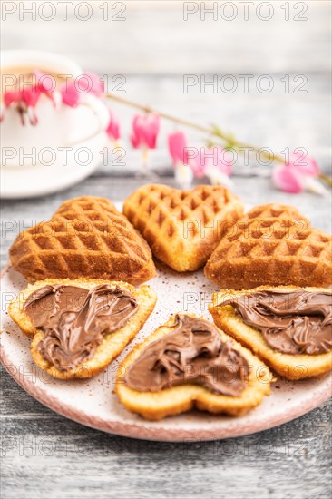 Homemade waffle with chocolate butter and cup of coffee on a gray wooden background. side view, selective focus, close up
