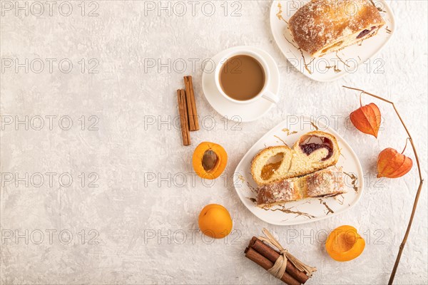 Homemade sweet bun with apricot jam and cup of coffee on gray concrete background. top view, flat lay, copy space