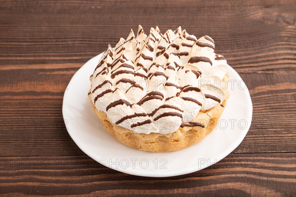 Tartlets with meringue cream and cup of coffee on brown wooden background. side view. Breakfast, morning, concept