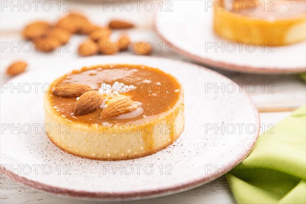 Sweet tartlets with almonds and caramel cream with cup of coffee on a white wooden background and green textile. side view, close up, selective focus