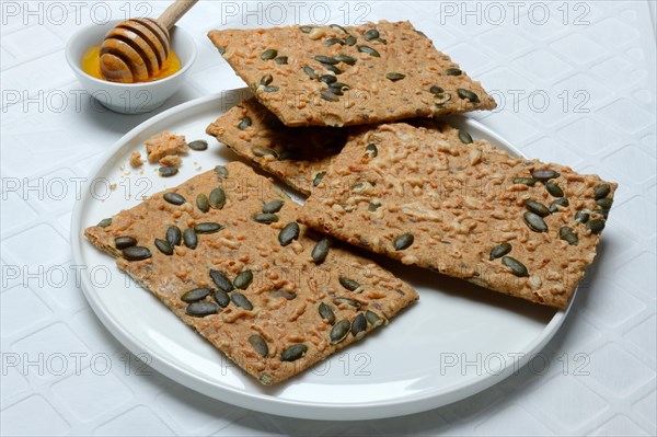 Crispbread with seeds and bowls of honey