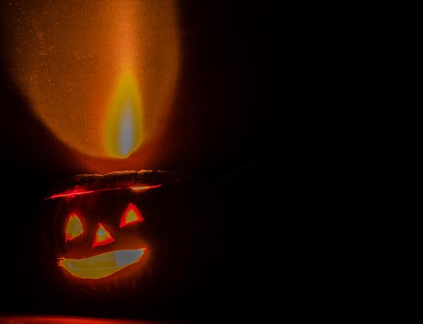 Lit Jack-O-Lantern casting reddish glow on black background in South Korea