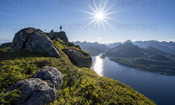 Mountaineer on the summit of Dronningsvarden or Stortinden, behind sea and fjord Umvagsundet, Sonnenstern, Vesteralen, Norway, Europe