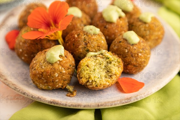 Falafel with guacamole on white concrete background and green linen textile. Side view, close up, selective focus