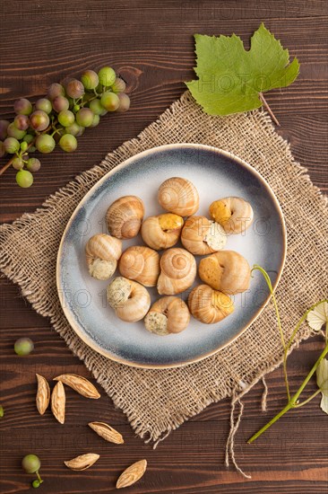 Grape (Burgundy) snails with butter and cheese on brown wooden background and linen textile. Top view, flat lay