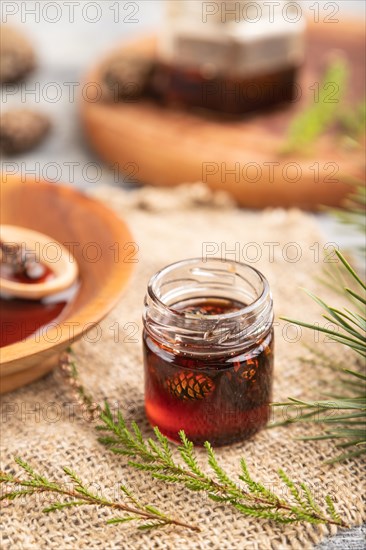 Pine cone jam with herbal tea on gray wooden background and linen textile. Side view, close up, selective focus