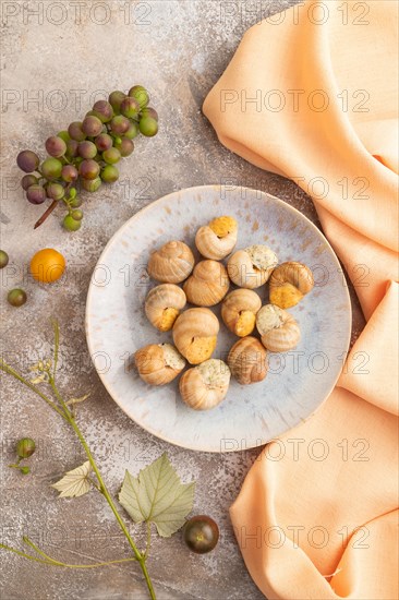 Grape (Burgundy) snails with butter and cheese on brown concrete background and orange textile. Top view, flat lay