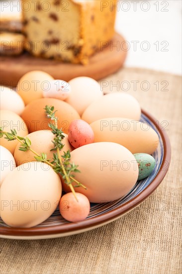 Homemade easter colored eggs on plate and raisins cake on a gray concrete background and linen textile. side view, close up, selective focus