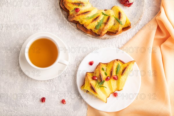 Cheesecake with cup of green tea on gray concrete background and orange linen textile. top view, flat lay, close up