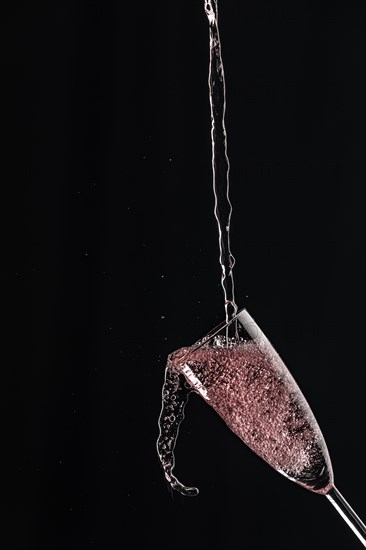 A dynamic shot of an overflowing champagne glass with splashes and contrasts