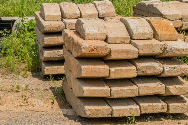 Curved concrete bricks used to support large utility poles stacked in rural countryside