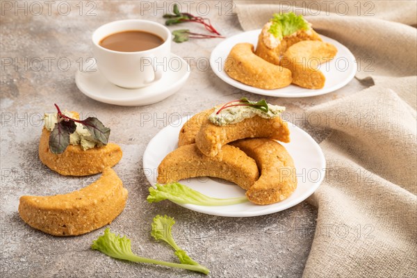 Homemade salted crescent-shaped cheese cookies, cup of coffee on brown concrete background and linen textile. side view, close up