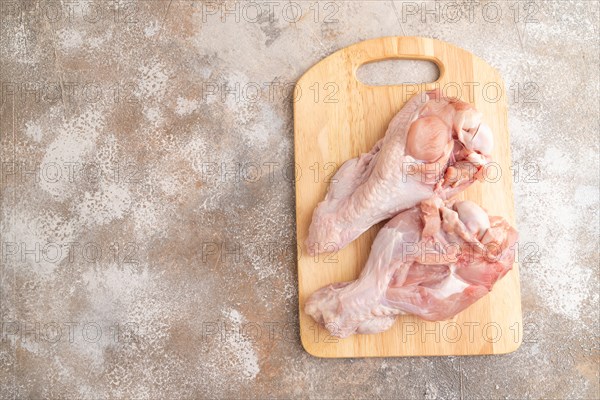 Raw turkey wing with herbs and spices on a wooden cutting board on a brown concrete background. Top view, flat lay, copy space