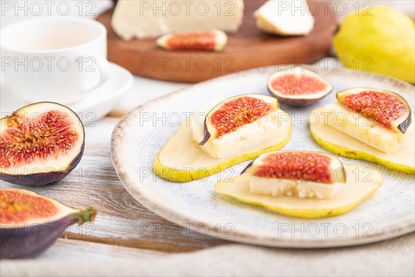 Summer appetizer with pear, cottage cheese, figs and honey on a white wooden background and linen textile. Side view, close up, selective focus