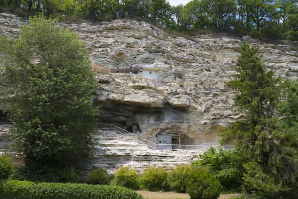 View of cave dwellings in a large rock face surrounded by trees and greenery, Aladja Monastery in 2 levels, Aladja Monastery, Aladzha Monastery, medieval rock monastery, cave monastery in limestone cliff, Varna, Black Sea coast, Bulgaria, Europe