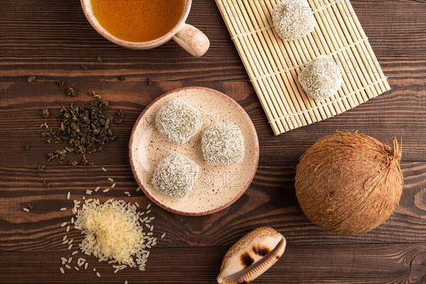 Japanese rice sweet buns mochi filled with pandan and coconut jam and cup of green tea on brown wooden background. top view, flat lay, close up