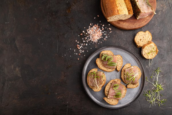 Bread sandwiches with jerky salted meat, sorrel and cilantro microgreen on black concrete background. top view, flat lay, copy space