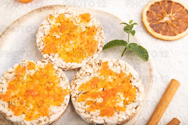 Carrot jam with puffed rice cakes on gray concrete background. Side view, close up, selective focus