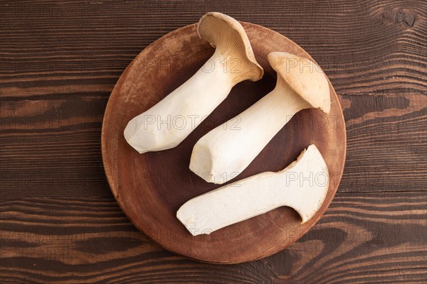 King Oyster mushrooms or Eringi (Pleurotus eryngii) on brown wooden background. Top view, flat lay