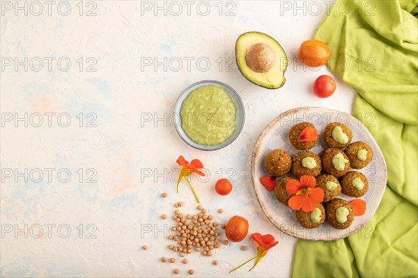 Falafel with guacamole on white concrete background and green linen textile. Top view, flat lay, copy space