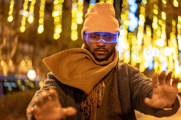 African futuristic man gesturing while using smart goggles in the city at night