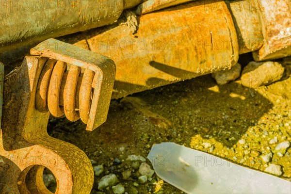 Closeup of rusted metal industrial machine parts discarded and laying on the ground