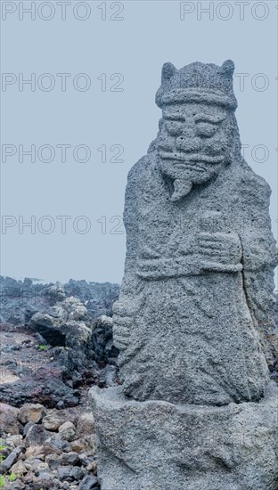 Ancient stone carved figure of sea god on coast of Jeju island, South Korea, Asia