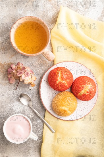 Traditional french custard dessert shu cake and cup of green tea on brown concrete background and yellow linen textile. top view, flat lay. Breakfast, morning, concept