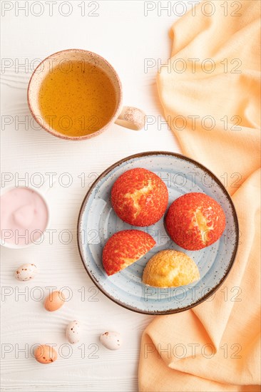 Traditional french custard dessert shu cake and cup of green tea on white wooden background and orange linen textile. top view, flat lay, close up. Breakfast, morning, concept