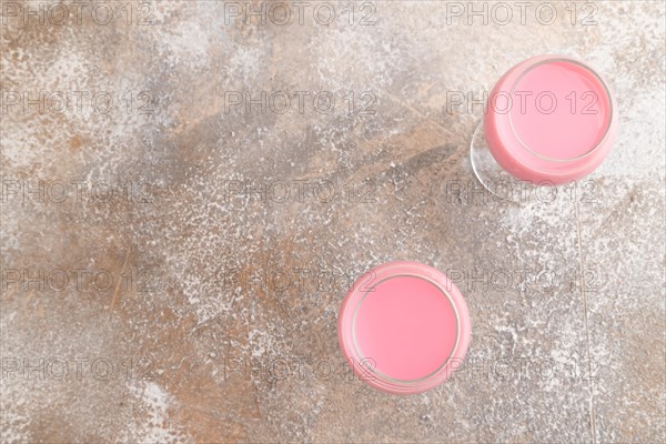 Sweet strawberry liqueur in glass on a gray concrete background. top view, copy space, flat lay